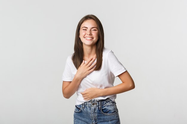 Felice bella ragazza ridendo e toccando il petto, guardando grato