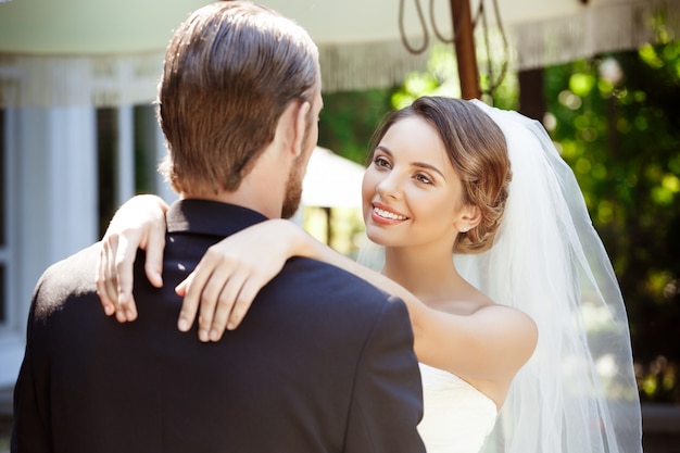 Felice bella sposi sorridenti, abbracciando, guardandosi l'un l'altro.