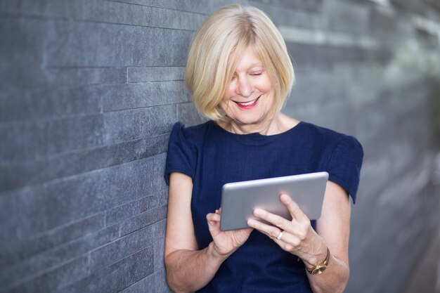 Felice businesswoman senior utilizzando tablet digitale