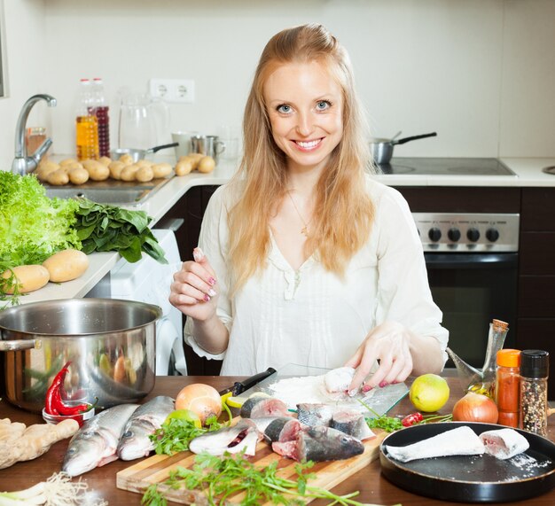 Felice casalinga che cucina pesce di mare in farina