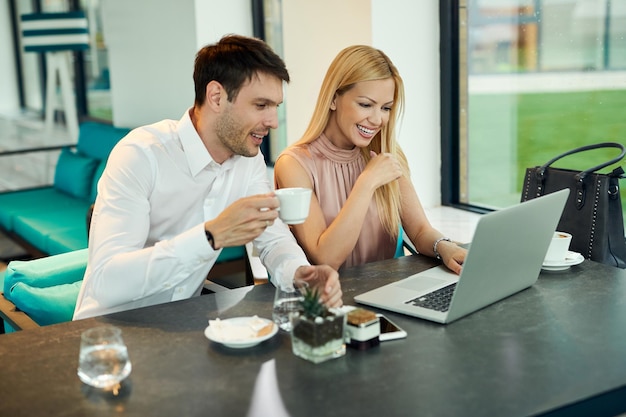 Felice coppia d'affari utilizzando computer mentre bevendo caffè in un bar Focus è sulla donna