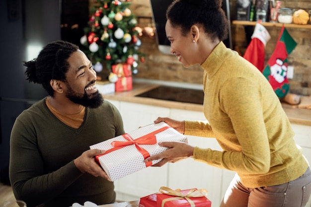 Felice coppia nera che scambia i regali di Natale a casa