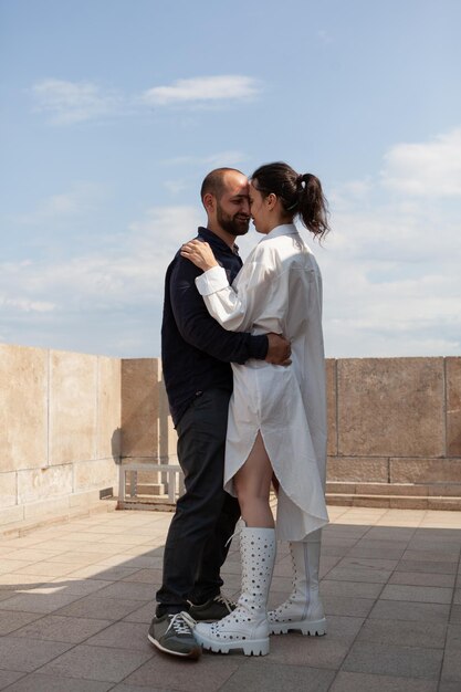 Felice coppia romantica che si abbraccia durante l'anniversario della relazione in piedi sul tetto della torre godendo di guardare la vista panoramica della città metropolitana dal punto di osservazione. Paesaggio dell'edilizia urbana