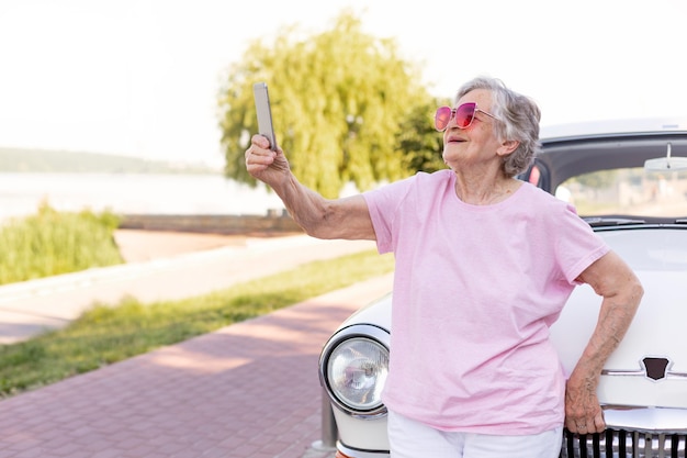 Felice donna anziana in piedi accanto alla sua auto