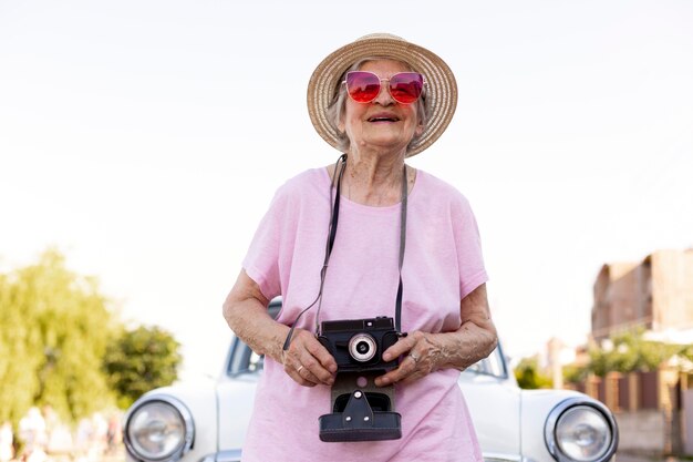 Felice donna anziana in piedi accanto alla sua auto