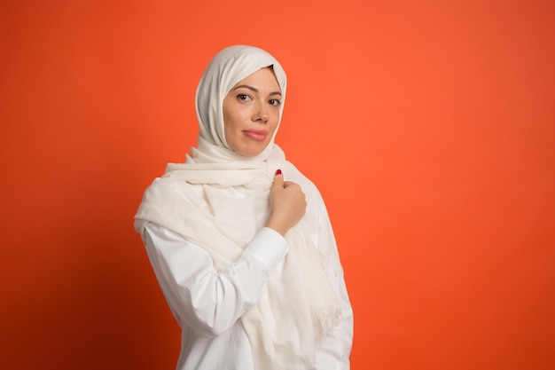 Felice donna araba in hijab. Ritratto di ragazza sorridente, che propone al fondo rosso dello studio.