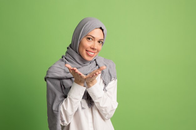 Felice donna araba in hijab. Ritratto di ragazza sorridente, che propone allo sfondo verde studio.