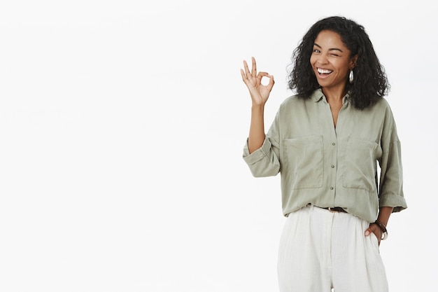 Felice donna di successo in camicia alla moda e pantaloni che sbattono le palpebre e sorridono felici