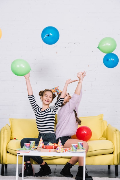 Felice due ragazze che godono di lancio palloncini in aria in festa