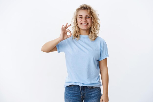 Felice e compiaciuta cliente femminile con capelli biondi corti e un sorriso gioioso soddisfatto che mostra un gesto e un sorriso ok