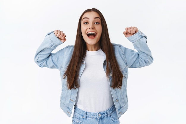 Felice eccitato donna bruna carina che celebra alzando le mani saltando dalla felicità e felice di raggiungere il successo facendo il tifo per qualcuno che tifa come un vero fan incoraggiare l'amico a vincere