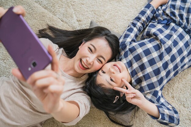 Felice famiglia asiatica madre e figlia che fanno una foto selfie mentre l'uso nello sfondo della casa del soggiorno