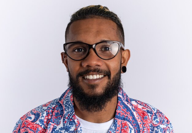 Felice giovane afroamericano in maglietta colorata con gli occhiali guardando la telecamera sorridendo allegramente