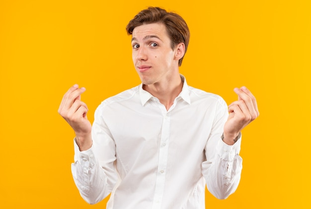 Felice giovane bel ragazzo che indossa una camicia bianca che mostra il gesto di punta isolato sul muro arancione orange