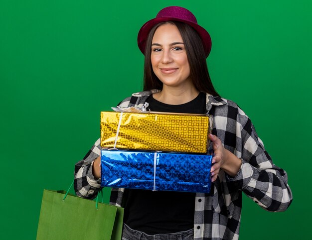 Felice giovane bella ragazza che indossa un cappello da festa con scatole regalo con sacchetto regalo