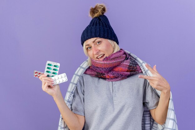 Felice giovane bionda malata donna slava che indossa sciarpa e cappello invernale