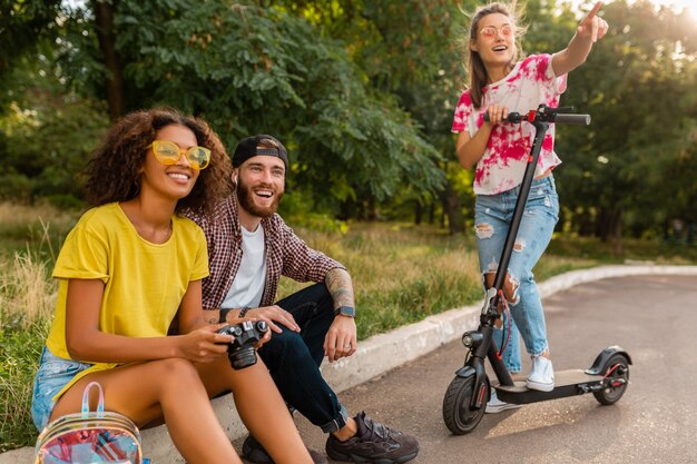 Felice giovane compagnia di amici sorridenti nel parco, uomo e donna divertendosi trascorrendo del tempo insieme visitando la fotocamera