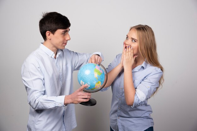 Felice giovane coppia che pianifica la destinazione dell'anniversario con in mano un globo.