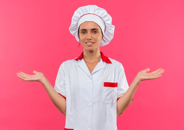 Felice giovane cuoco femminile che indossa l'uniforme dello chef diffonde le mani