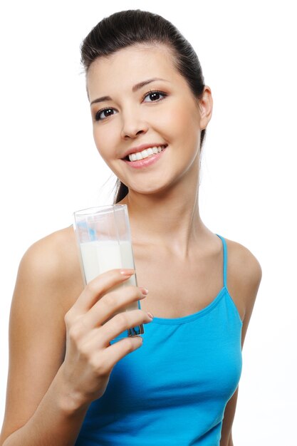 Felice giovane donna attraente con un bicchiere di latte in mano