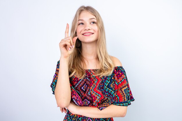 Felice giovane donna bionda che punta verso l'alto