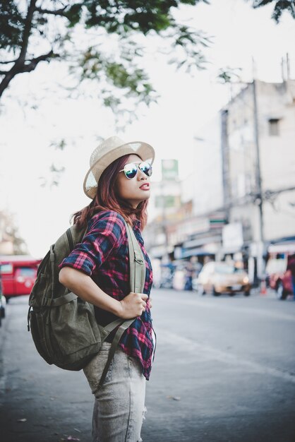 Felice giovane donna hipster portare zaino, Viaggiatore donna turistica con zaino all&#39;aperto durante le vacanze. Concetto di stile di vita delle donne.