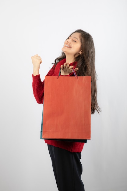 Felice giovane donna in maglione che tiene i sacchetti della spesa colorati.