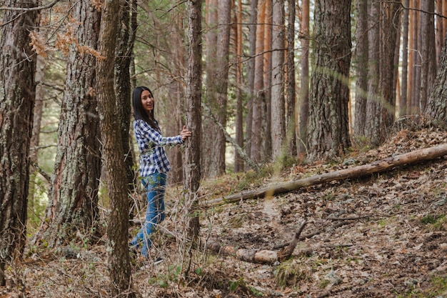 Felice giovane donna in posa accanto a un albero