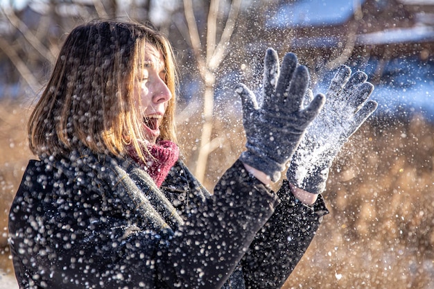 Felice giovane donna in una passeggiata in inverno con la neve nelle sue mani