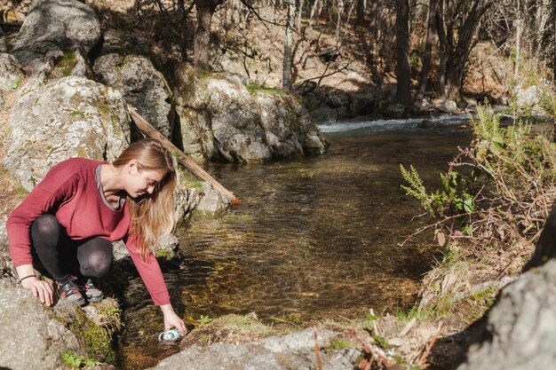 Felice giovane donna, riempiendo la sua bottiglia d&#39;acqua