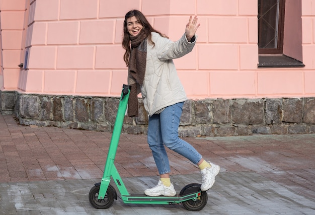 Felice giovane donna su scooter elettrico in città.