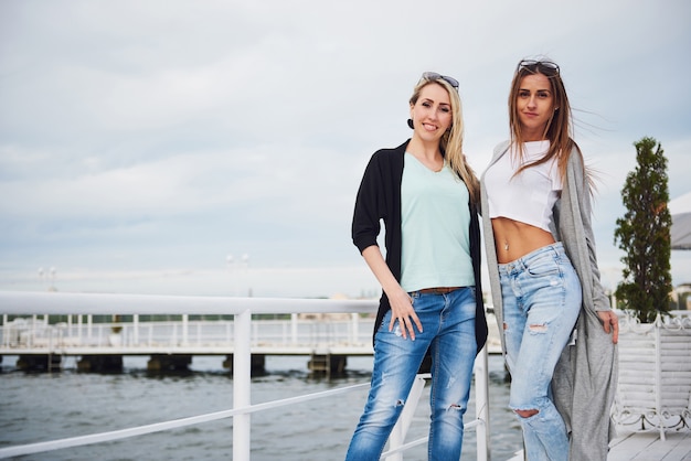 Felice giovane ragazza in eleganti marchi di abbigliamento sul molo vicino all'acqua.