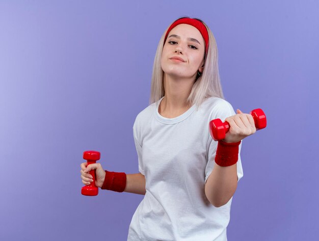 Felice giovane ragazza sportiva caucasica con le parentesi graffe che indossa la fascia