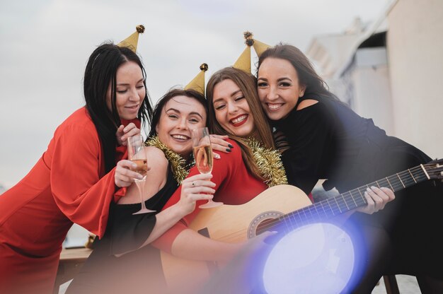 Felice gruppo di donne che suonano la chitarra sulla festa sul tetto