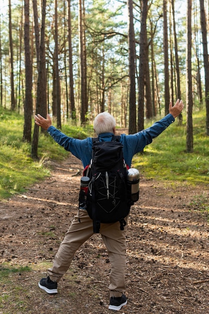 Felice l'uomo anziano con le braccia aperte zaino in spalla in natura