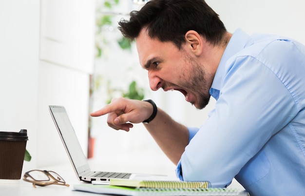 Felice libero professionista maschio che comunica con un amico all'estero utilizzando un computer portatile Bell'uomo che ha una pausa durante il lavoro