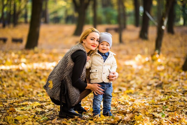 Felice madre e figlio stanno giocando nel parco in autunno