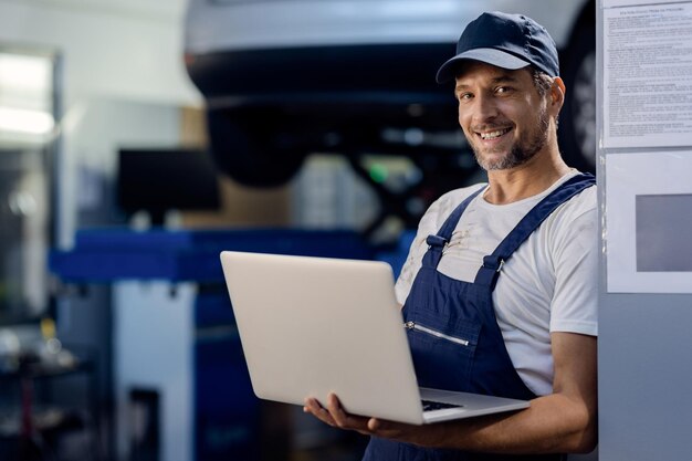 Felice meccanico che lavora su un computer in officina