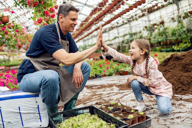 Felice padre e figlia che danno il cinque dopo aver piantato fiori al vivaio