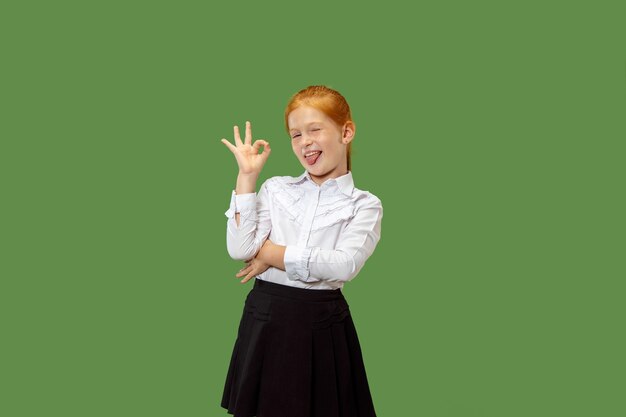 Felice ragazza adolescente in piedi, sorridente e indicando se stesso isolato su sfondo verde alla moda per studio. Bellissimo ritratto femminile a mezzo busto. Emozioni umane, concetto di espressione facciale.