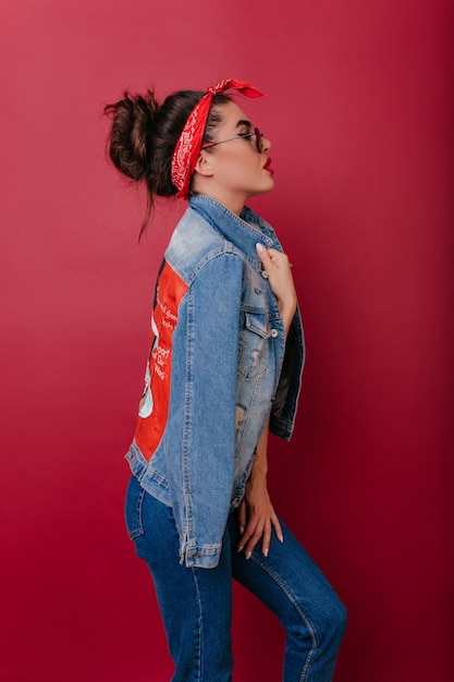 Felice signora in abito di jeans casual in piedi in posa sicura durante il servizio fotografico