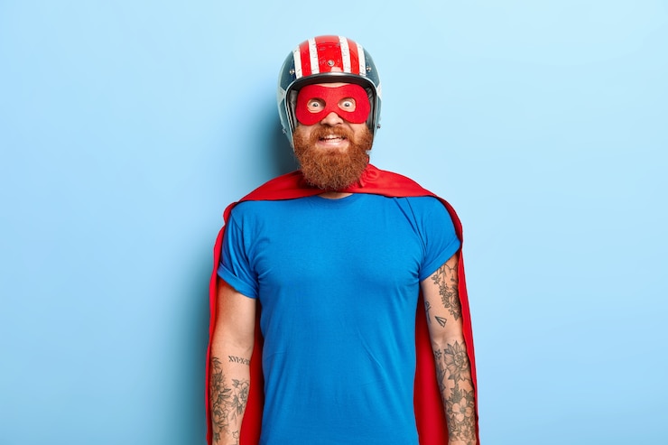 Foto gratuito felice uomo barbuto con una prospettiva divertente, arriva alla festa in costume, essendo un personaggio di supereroi