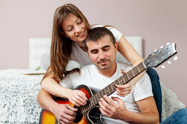 Felice uomo e donna a suonare la chitarra