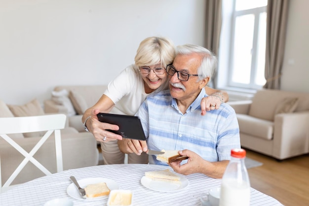 Felice vecchia famiglia coppia parlando con i nipoti utilizzando tablet sorpreso donna anziana eccitata guardando tablet sventolando e sorridente