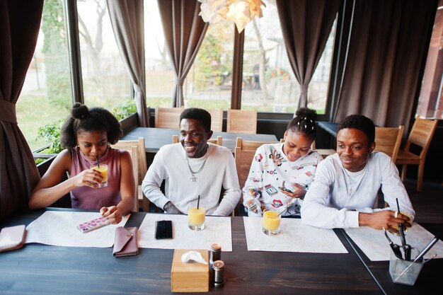 Felici amici africani seduti e in chat al bar Gruppo di persone di colore che si incontrano e bevono succo nel ristorante