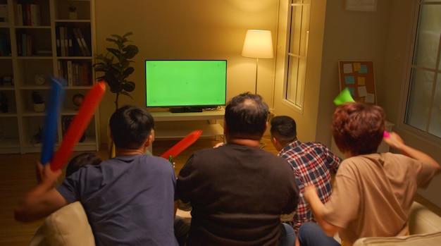 Felici amici asiatici o tifosi di calcio che guardano il calcio sullo schermo verde Chroma Key