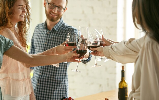 Felicità. Persone che tintinnano bicchieri di vino o champagne.