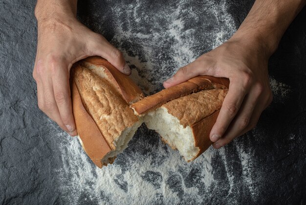 FeMale mani rompendo il pane appena sfornato, vista dall'alto.
