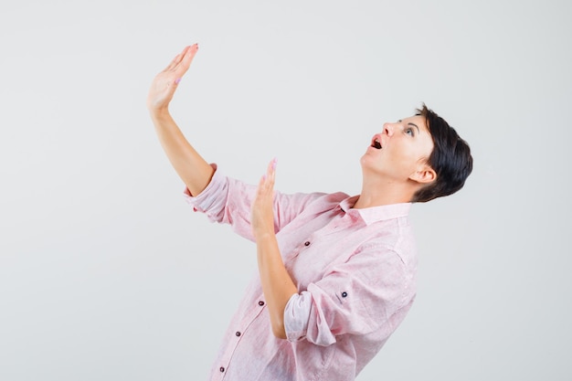 Femmina alzando le mani in modo preventivo in camicia rosa e guardando spaventata. .