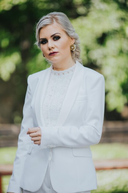 Femmina caucasica alla moda elegante in un vestito bianco grazioso e pantaloni che posano per il servizio fotografico di moda